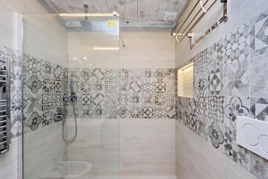 Glass shower with patterned tiles and overhead shower head