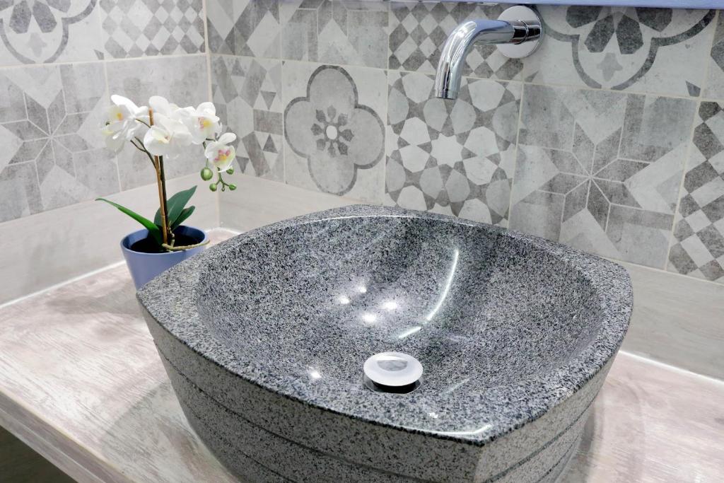 Stone vessel basin beside an orchid and patterned tiles