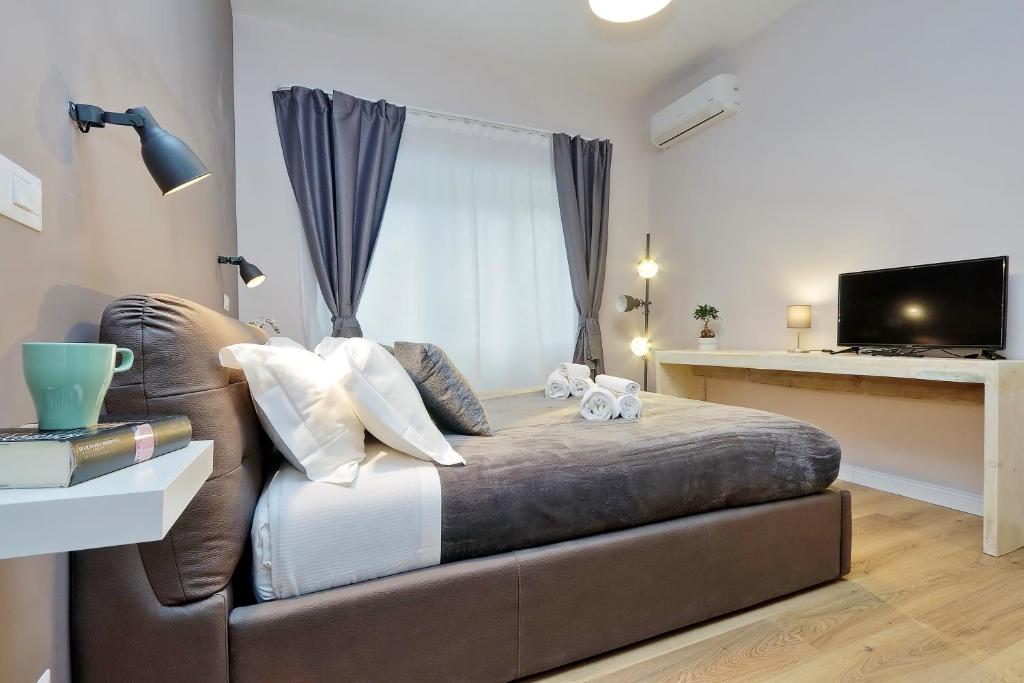 Double bed facing a television, with curtains and air conditioning