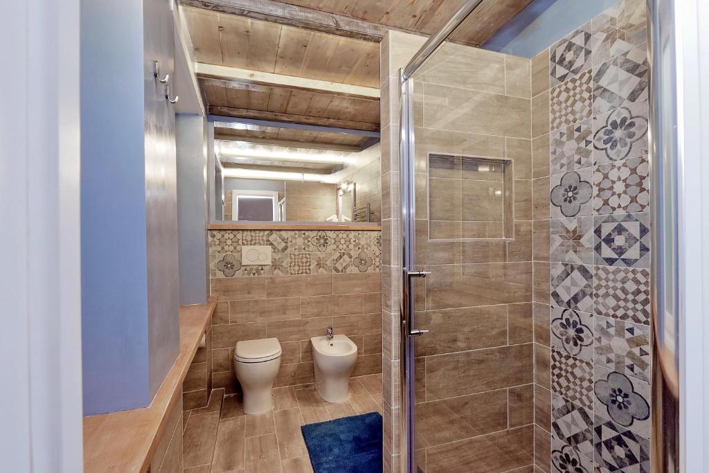 Bathroom with glass shower, toilet, bidet and patterned tiles
